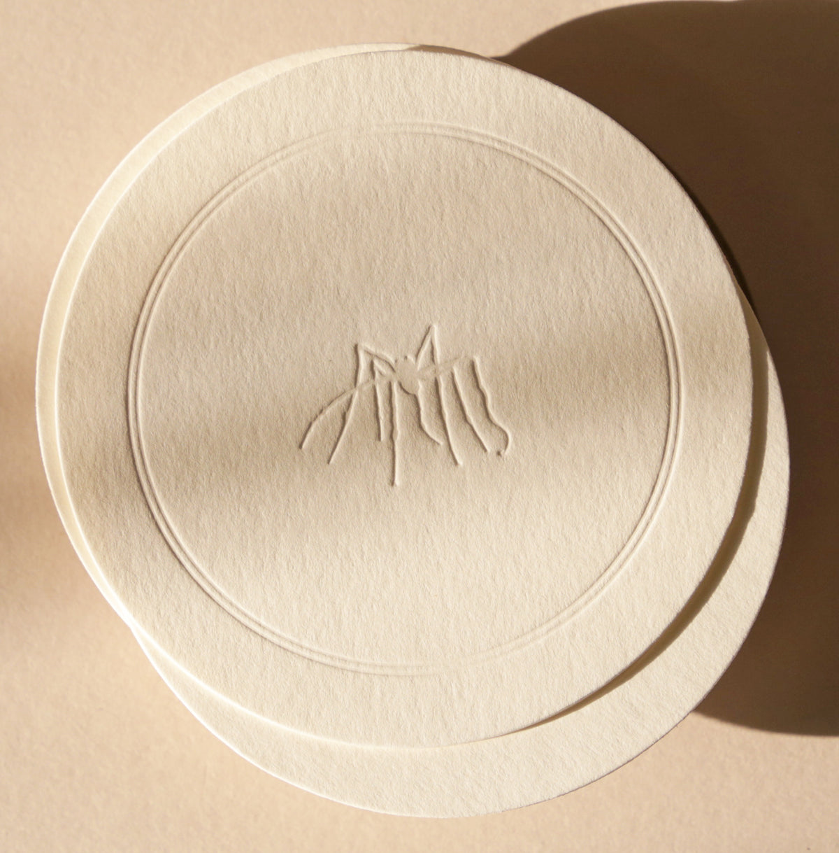 Round beige object with a logo on a beige background