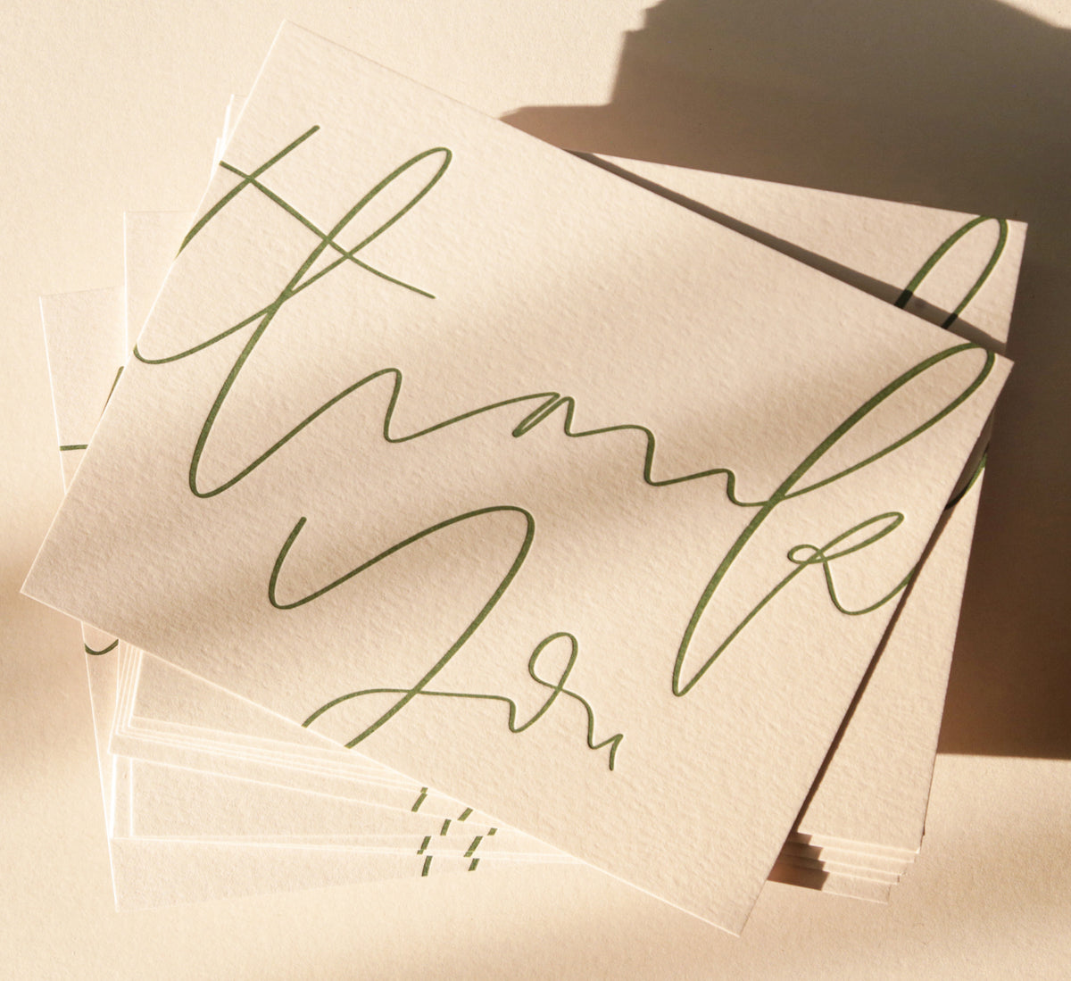 Stack of beige napkins with green cursive text on a neutral background